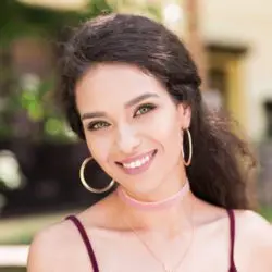 Brunette woman with psychic abilities in foreground and building with plants in background