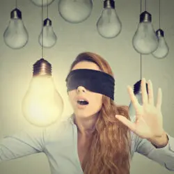 image of a blindfolded woman wandering through lightbulbs trusting her intuition
