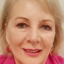 psychic marita has blonde hair and blue eyes wearing a pink scarf.