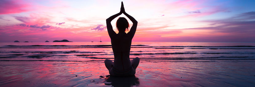 image of woman meditating in the pink sundown
