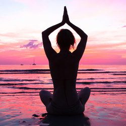 image of woman meditating in the pink sundown