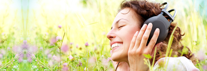 image of woman blissfully happy lying in the grass listening to music