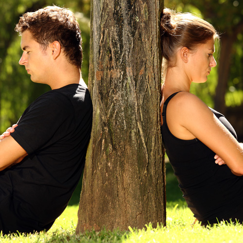 image of man and woman looking depressed sitting against a tree in the park