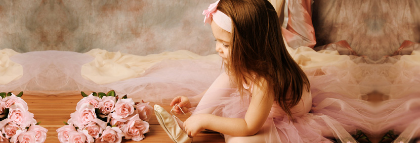 image of a little ballerina girl in a pink tutu putting on her ballet shoes