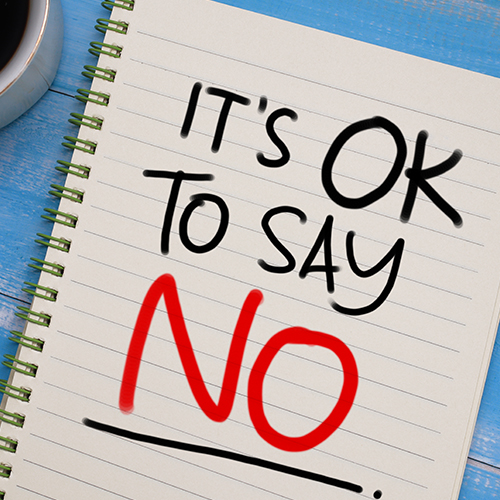 The words "It's OK to say no" written in black and red text on a notebook