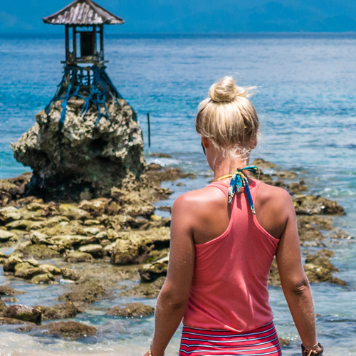 Blonde woman walking towards a tiny temple near the ocean