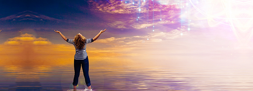 woman standing in the water looking up at glowing clouds feeling rejuvenated