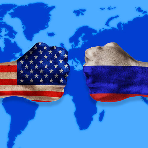 Two hands fist bumping showing flag of the USA and flag of Russia on their hands representing the Cold War