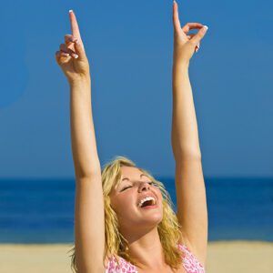 woman on the beach with closed eyes extending her pointed fingers to the sky representing a number 1 personality