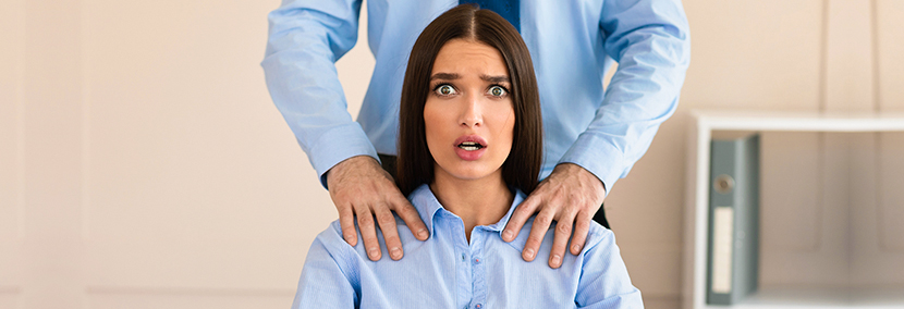 woman with long brown hair being inappropriately touched by a co-worker