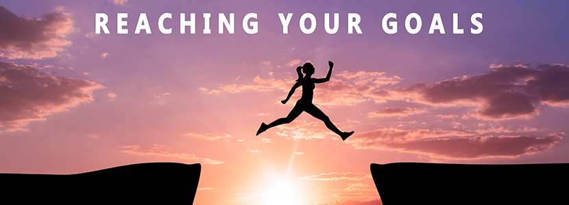 silhouette of a woman jumping from one cliff edge to another cliff edge symbolsing reaching her goals