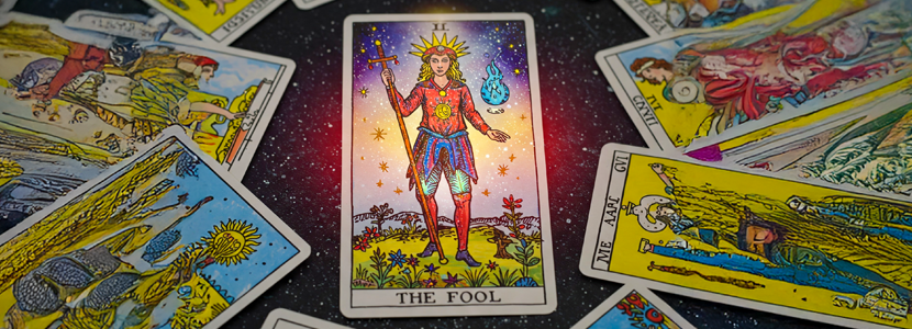 Bright and modern 16:9 banner featuring The Fool Tarot card as the central focus, surrounded by a spread of other tarot cards. The Fool card is depicted with vibrant colors and a slightly mystical aesthetic, showcasing the figure of the Fool standing confidently with a staff and bundle, seemingly stepping off a cliff into a starlit expanse. The surrounding cards are arranged in a circular pattern, hinting at a reading or journey.