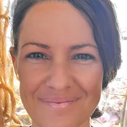 Close-up portrait of Ruby, an Australian psychic medium, smiling warmly with natural light in the background.