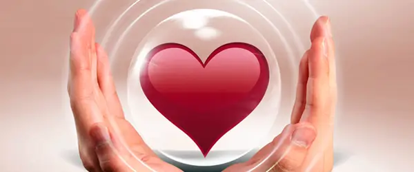 Hands making a circle with red glossy heart enclosed. Concentric white circles emanating from heart. All on pale apricot pink background.