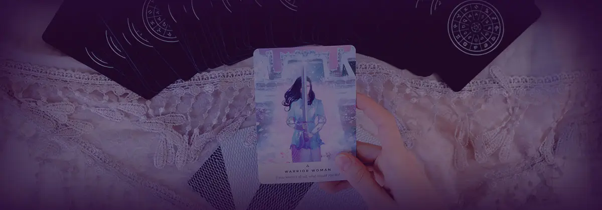dark purple background with lace, woman holding a blue Swords Tarot Card in foreground, indicating tarot readings