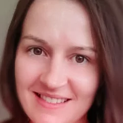 Psychic Jess smiling in a natural light headshot, brown hair, warm and approachable energy, professional psychic reader profile photo.