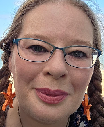 Psychic Christina smiling outdoors wearing glasses and star earrings